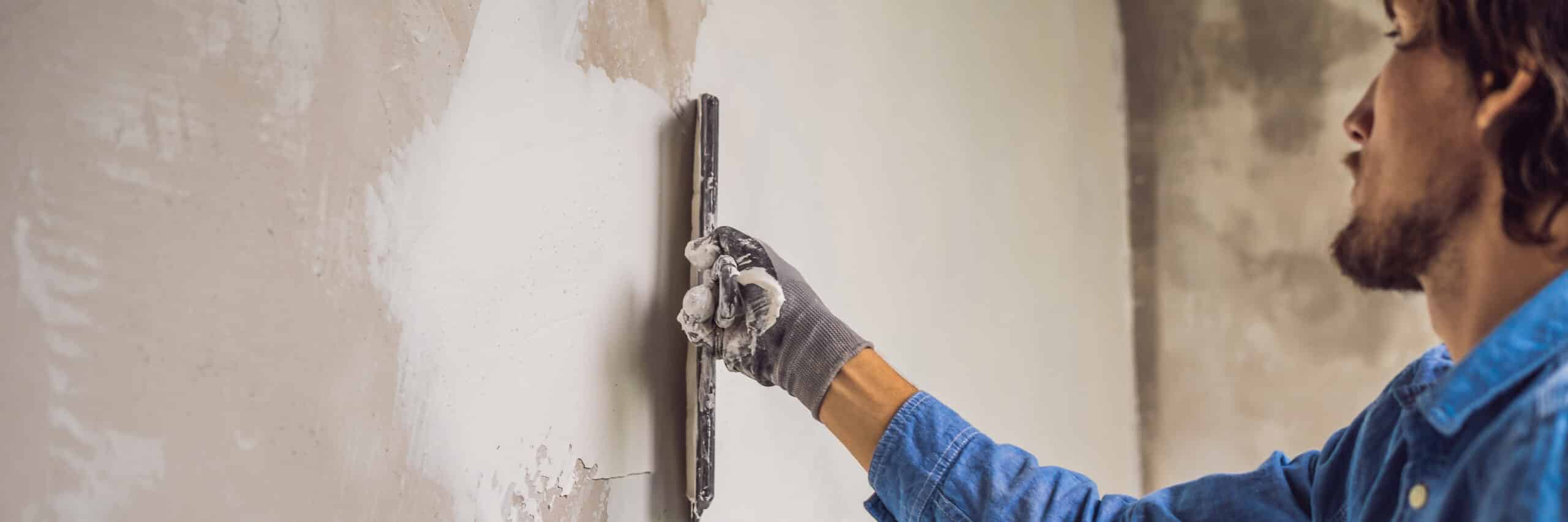 Handwerker glättet eine Wand mit einer Glättkelle als Vorbereitung für die Tapete